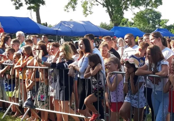 Grupa ludzi stojących za barierką podczas IX edycji Dni Bulkowa na otwartym terenie, z niebieskimi namiotami w tle.