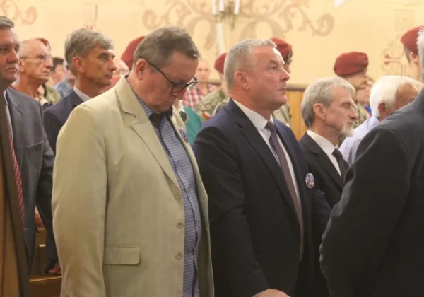 Grupa mężczyzn w garniturach i marynarkach stoi w kościelnym wnętrzu podczas Kongresu Trzeźwości Diecezji Płockiej w Starej Białej, a w tle widać uczestników w czerwonych beretach.