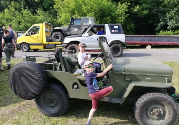Dwoje dzieci siedzi za kierownicą zielonego terenowego jeep’a podczas prezentacji pojazdów na Terenowym Dniu Dziecka w Wyszogrądzie.