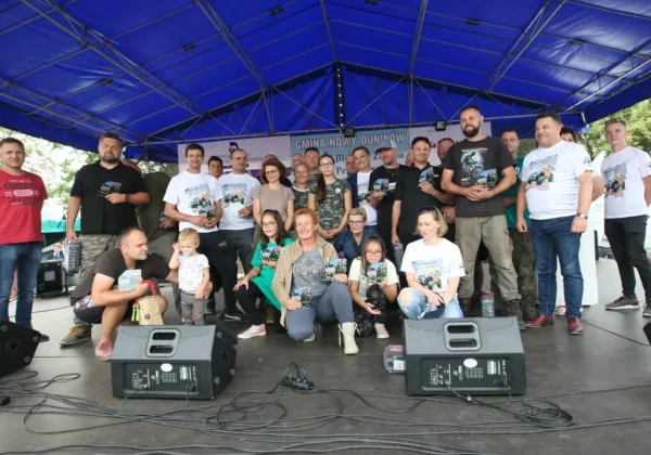 Grupa uczestników i organizatorów na scenie pod namiotem trzyma gadżety podczas rajdu 4×4 w gminie Nowy Duninów.