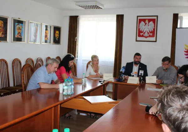 Konferencja prasowa dotycząca ASF: grupa osób siedzi przy długim stole w sali konferencyjnej, z mikrofonami, notatkami i butelkami wody.