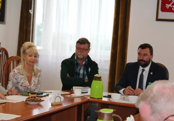 Kilka osób siedzi przy stole w sali konferencyjnej i omawia temat ASF na Posiedzeniu Powiatowego Zespołu Zarządzania Kryzysowego.