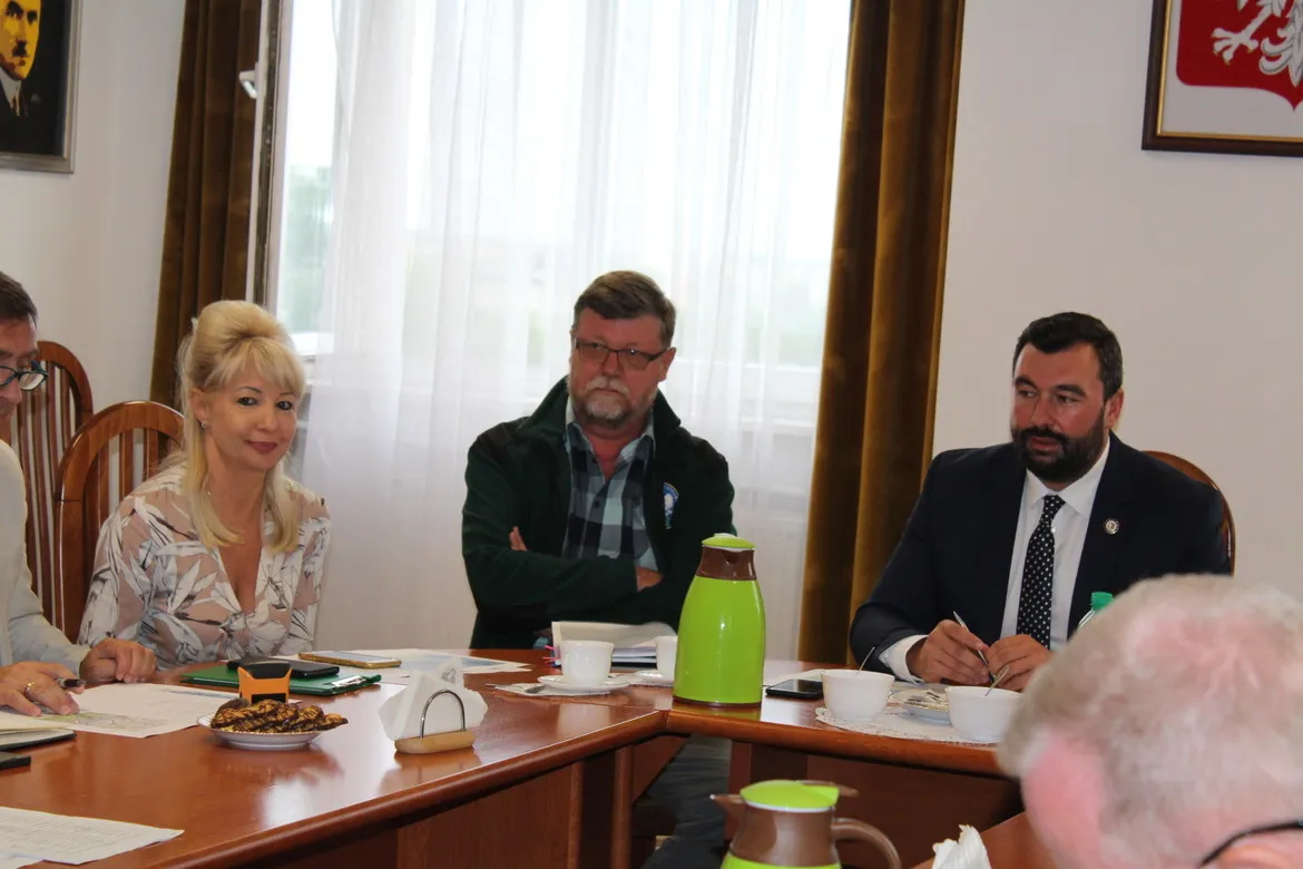 Kilka osób siedzi przy stole w sali konferencyjnej i omawia temat ASF na Posiedzeniu Powiatowego Zespołu Zarządzania Kryzysowego.