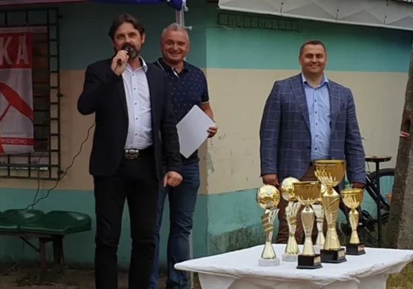 Trzech mężczyzn stoi przy stole z pucharami podczas ceremonii wręczania nagród na Turnieju Piłkarskim o Puchar Starosty Płockiego.