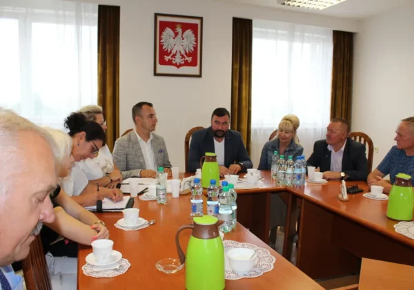 Grupa osób siedzi przy długim stole konferencyjnym podczas spotkania Zarządu Stowarzyszenia Sołtysów Powiatu Płockiego; na ścianie wisi godło Polski.