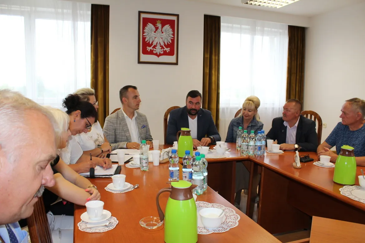 Grupa osób siedzi przy długim stole konferencyjnym podczas spotkania Zarządu Stowarzyszenia Sołtysów Powiatu Płockiego; na ścianie wisi godło Polski.