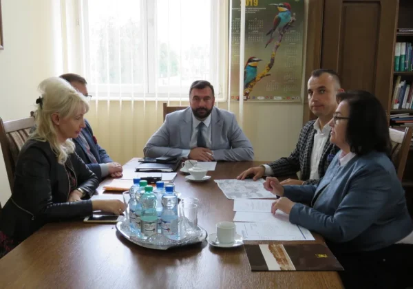 Grupa pięciu osób siedzi przy stole w biurze i omawia dokumenty na temat gazyfikacji Płocka i powiatu płockiego.