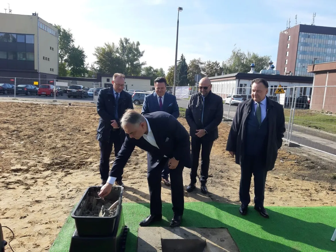 Grupa mężczyzn w garniturach podczas ceremonii wmurowania kamienia węgielnego pod budowę Kompleksu Opieki Długoterminowej i Hospicyjnej w Wojewódzkim Szpitalu Zespolonym w Płocku.