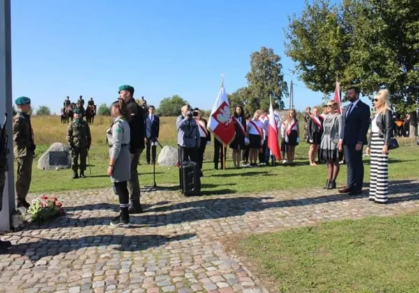 Uroczystość upamiętniająca Bitwę nad Bzurą w Wyszogrodzie: żołnierze w mundurach i mieszkańcy ze flagami stoją przy pomniku i składają wieńce.