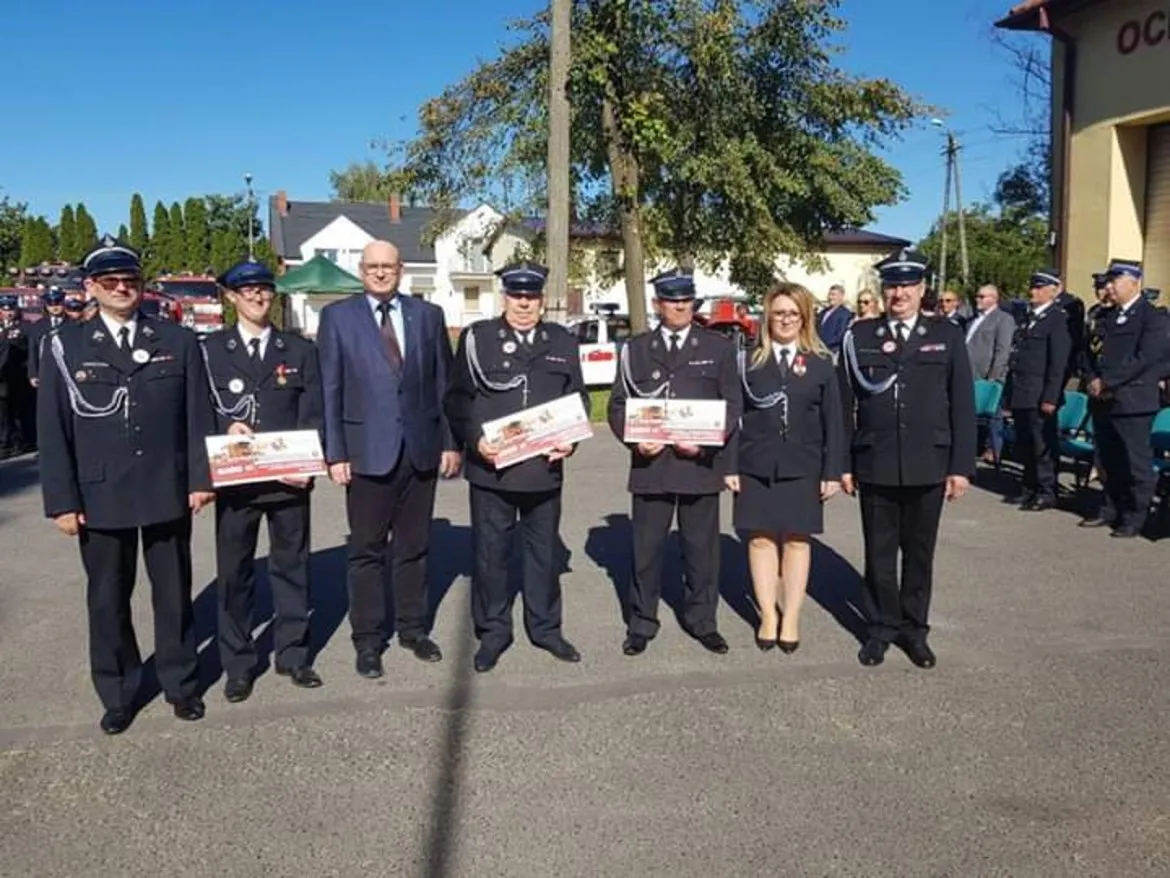 Grupa strażaków OSP Bielsk w mundurach galowych stoi na placu, trzymając certyfikaty podczas jubileuszowej uroczystości 110-lecia istnienia jednostki.