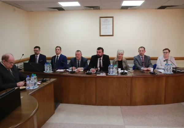 Grupa osób w formalnych ubraniach siedzi przy długim stole z mikrofonami i butelkami wody podczas XI sesji Rady Powiatu w Płocku w kadencji 2018–2023.