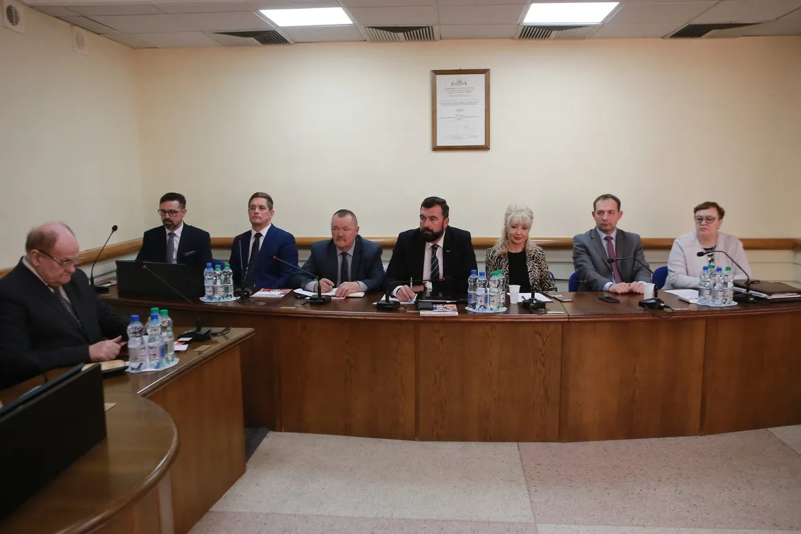 Grupa osób w formalnych ubraniach siedzi przy długim stole z mikrofonami i butelkami wody podczas XI sesji Rady Powiatu w Płocku w kadencji 2018–2023.