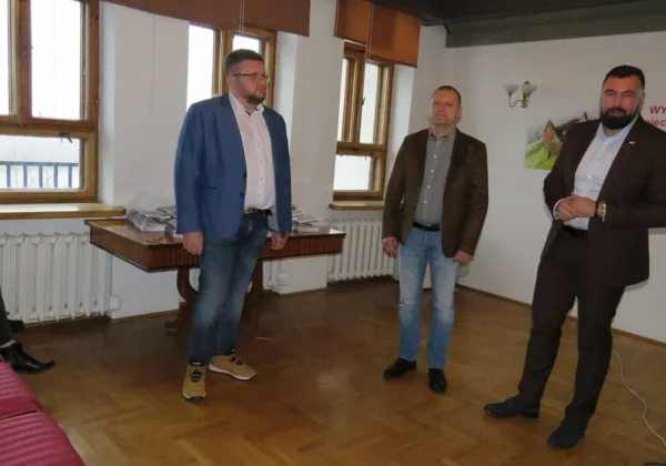 Trzech mężczyzn stoi w sali z oknami i biurkiem, prezentując nową publikację o Ziemi Płockiej i jej roli w tworzeniu Niepodległości.