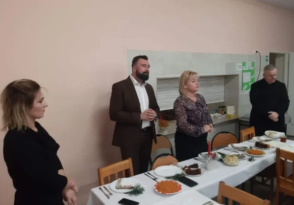 Cztery osoby stoją przy długim, świątecznie nakrytym stole w szkolnej stołówce podczas świątecznego spotkania w Zespole Szkół w Wyszogrodzie.