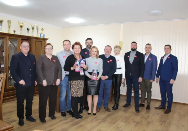Grupa osób stoi w sali podczas inauguracji 28. Finału Wielkiej Orkiestry Świątecznej Pomocy, a kilka z nich trzyma plakaty WOŚP.