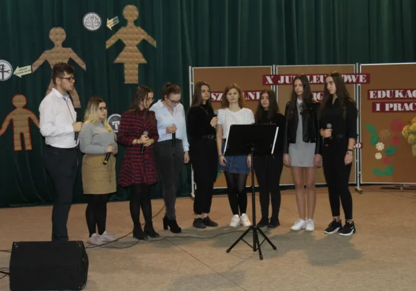 Grupa uczniów stoi na scenie z mikrofonami podczas X Jubileuszowych Szkolnych Targów Edukacji i Pracy w Zespole Szkół im. St. Staszica w Gąbinie.