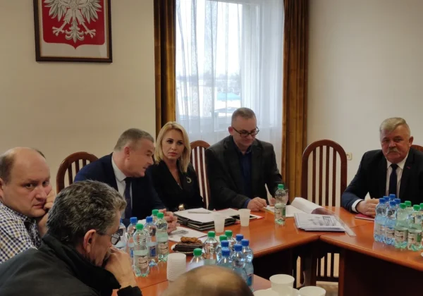 Grupa osób siedzi przy długim stole i omawia możliwości pozyskiwania środków finansowych dla jednostek OSP.