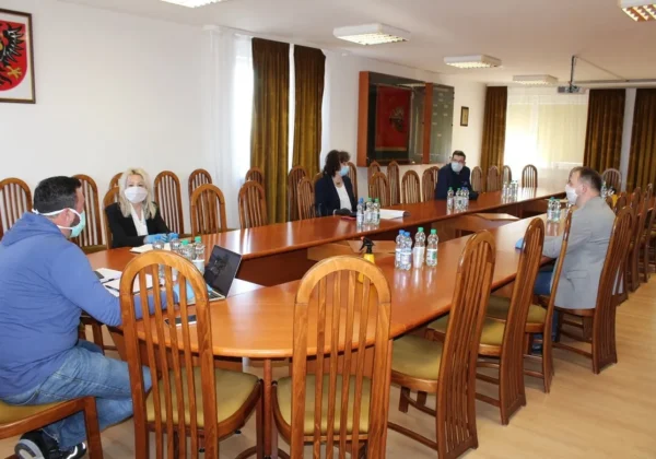 Grupa osób w maseczkach siedzi przy długim stole w sali konferencyjnej urzędu, prowadząc spotkanie o wsparciu dla przedsiębiorców, z butelkami wody na stole.