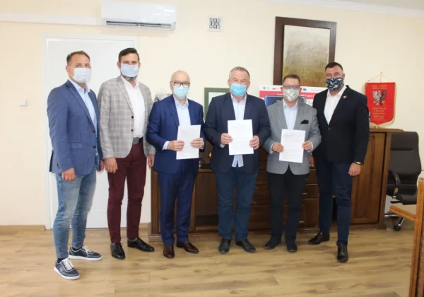 Sześciu mężczyzn w garniturach i maseczkach stoi w biurze, trzymając podpisane dokumenty, zapowiadając rozpoczęcie modernizacji drogi powiatowej nr 2904W Brudzeń Duży – Kamienica.