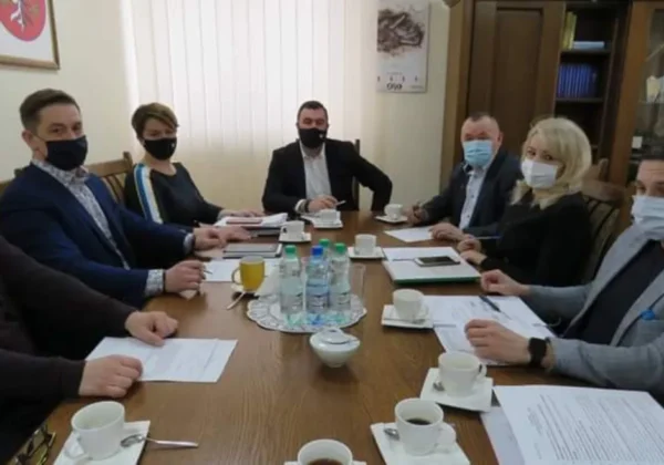 Grupa osób w maseczkach siedzi przy stole w sali konferencyjnej podczas marcowego posiedzenia Zarządu Powiatu Płockiego.