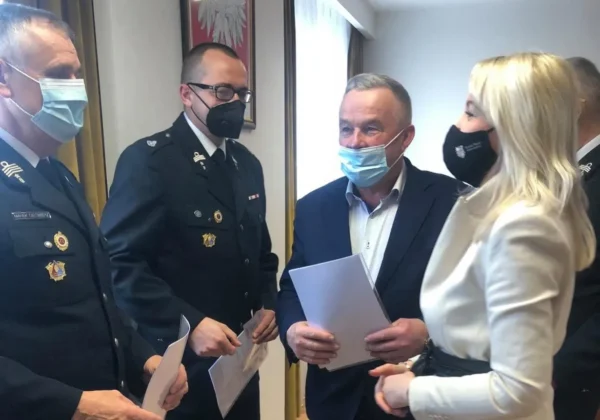 Trzej druhowie OSP w mundurach odbierają wyjątkowe wyróżnienia i certyfikaty od urzędników podczas oficjalnej ceremonii.