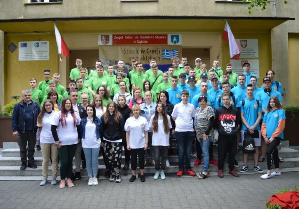 Grupa uczniów Zespołu Szkół im. Stanisława Staszica w Gąbinie na praktykach w Grecji, stojąca na schodach przed wejściem do budynku.
