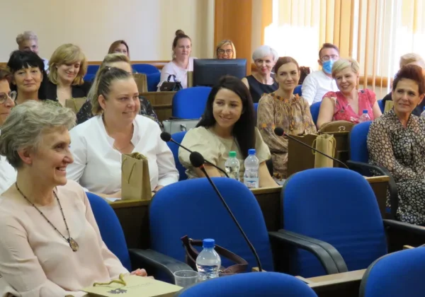 Grupa pracowników bibliotek, głównie kobiet, siedzi w sali konferencyjnej podczas spotkania z okazji Dnia Bibliotekarza.