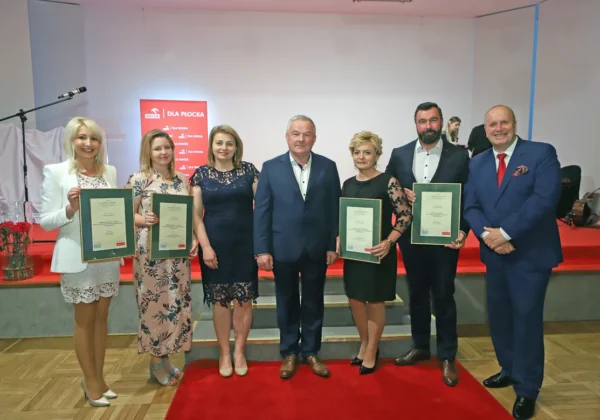 Grupa siedmiu laureatów plebiscytu Z Tumskiego Wzgórza stoi na scenie, trzymając certyfikaty.