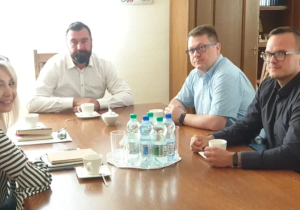 Cztery osoby (kobieta i trzech mężczyzn) siedzą przy stole podczas posiedzenia Powiatowego Sztabu Zarządzania Kryzysowego.