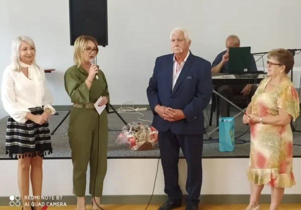 Czterech uczestników na scenie podczas Dnia Seniora w Bielsku; kobieta z mikrofonem przemawia, obok stoją mężczyzna i dwie kobiety, a w tle muzyk gra na keyboardzie.