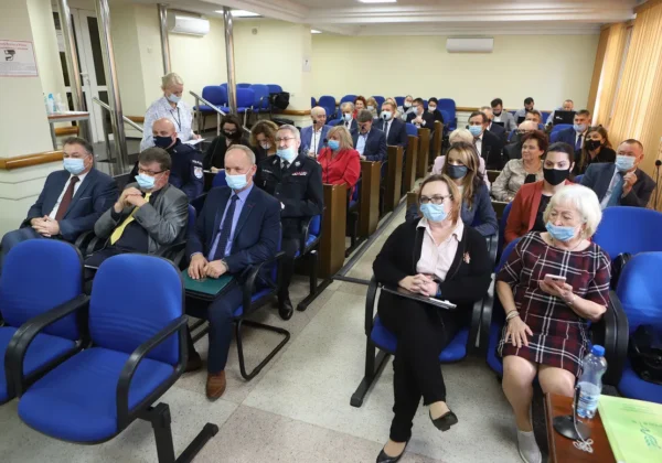 Uczestnicy XXIX sesji Rady Powiatu w Płocku siedzą w sali konferencyjnej, wszyscy w maseczkach i w formalnych strojach, podczas spotkania.