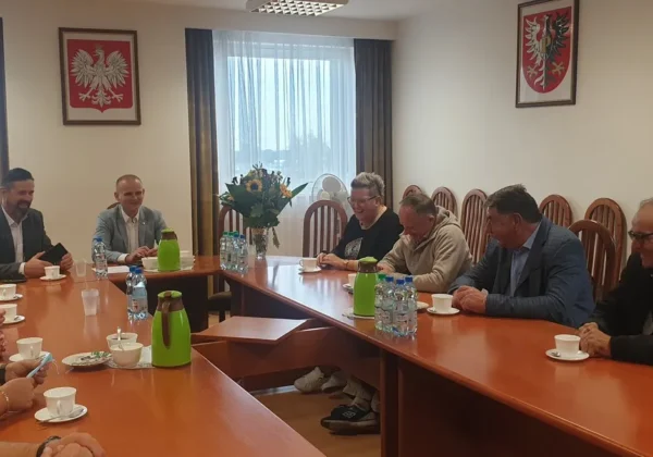 Grupa przedstawicieli Zarządu Stowarzyszenia Sołtysów Powiatu Płockiego podczas wizyty u Starosty Płockiego w sali konferencyjnej, siedzących przy dużym stole z kwiatami, napojami i filiżankami.