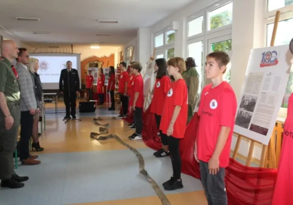 Młodzież w czerwonych koszulkach stoi w szeregu podczas otwarcia wystawy z okazji 100-lecia Związku Ochotniczych Straży Pożarnych RP.