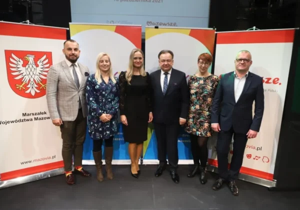 Grupa sześciu osób stoi na scenie między banerami z herbem województwa mazowieckiego i logotypami, prezentując inicjatywę mieszkańców na rzecz nowej ścieżki pieszo-rowerowej w powiecie płockim.