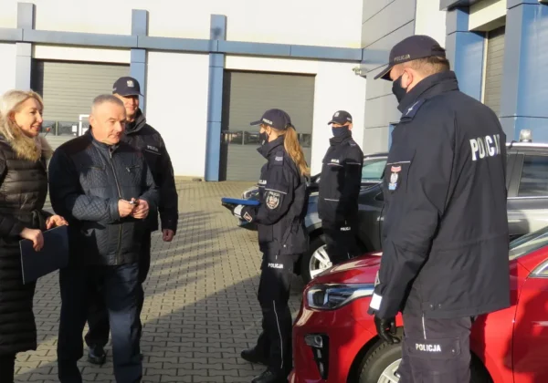 Grupa policjantów i cywilów stoi na placu przy nowym radiowozie policji w Wyszogrodzie.