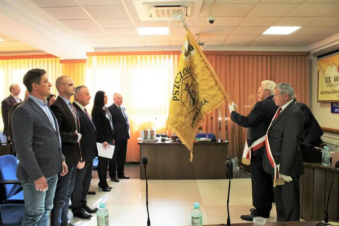 Członkowie Polskiego Związku Pszczelarzy w Płocku uczestniczą w ceremonii w Starostwie Powiatowym, gdzie przedstawiane są flagi i symbole pszczelarstwa.