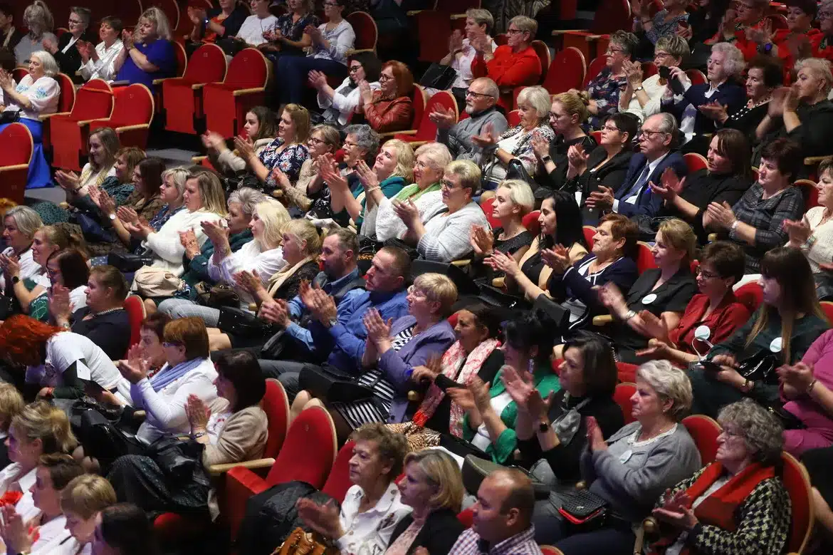 Grupa osób wśród publiczności, z entuzjazmem klaskająca w czasie wydarzenia.