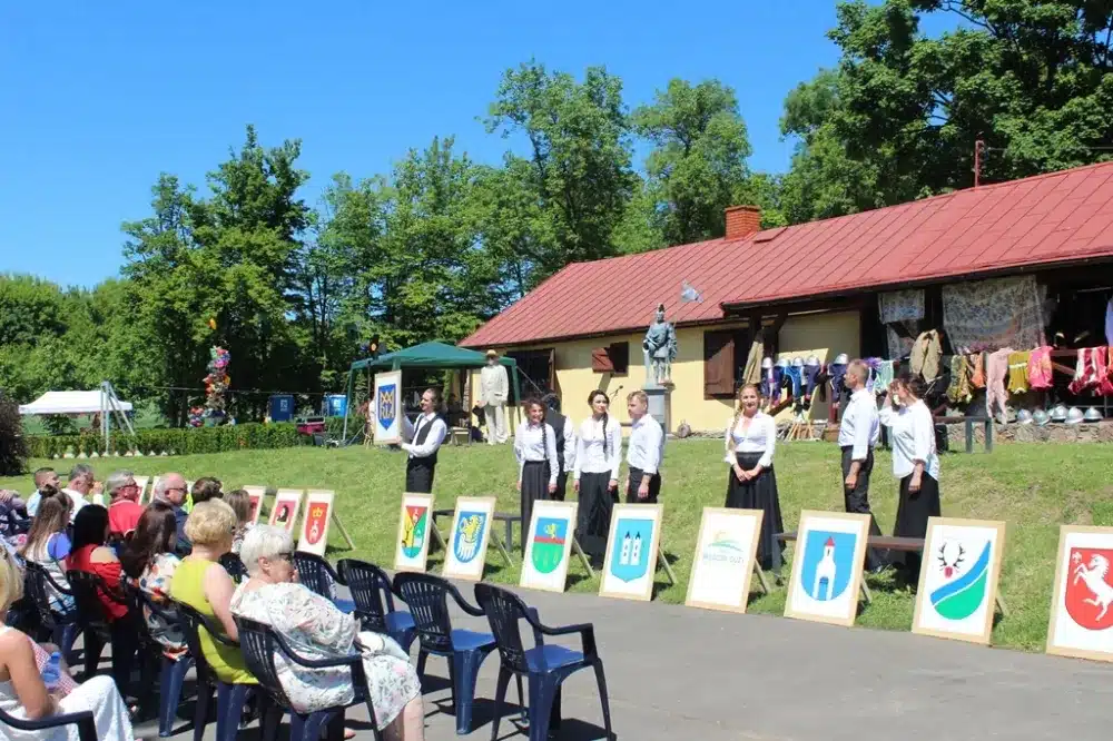 Uroczystość obchodów 100-lecia Ochotniczych Straży Pożarnych w powiecie płockim, z publicznością i przedstawicielami w strojach formalnych.