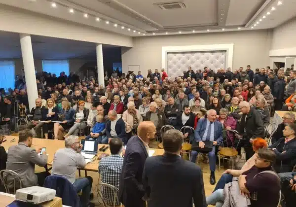 Zgromadzenie mieszkańców, którzy wyrażają sprzeciw wobec proponowanym wariantom linii kolejowej, podczas spotkania z udziałem starosty oferującego pomoc prawną.