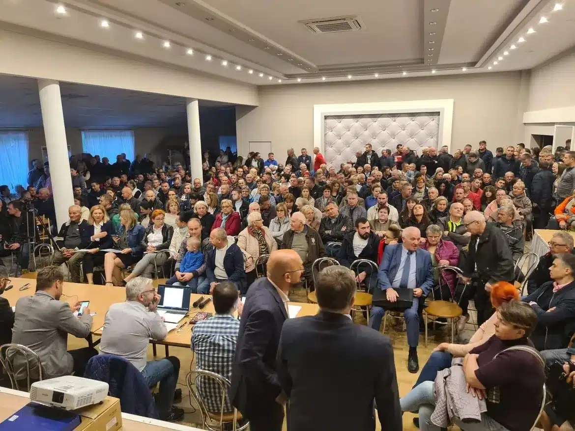 Zgromadzenie mieszkańców, którzy wyrażają sprzeciw wobec proponowanym wariantom linii kolejowej, podczas spotkania z udziałem starosty oferującego pomoc prawną.