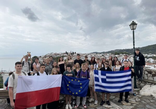 Zdjęcie grupowe uczniów z flagami Polski, Unii Europejskiej i Grecji