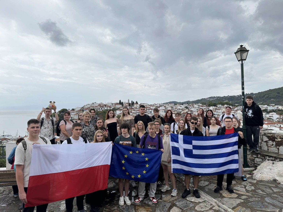 Zdjęcie grupowe uczniów z flagami Polski, Unii Europejskiej i Grecji