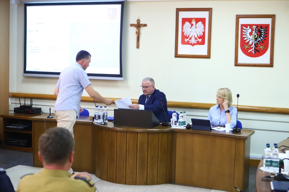 Radny przekazujący dokumenty przewodniczącemu rady powiatu