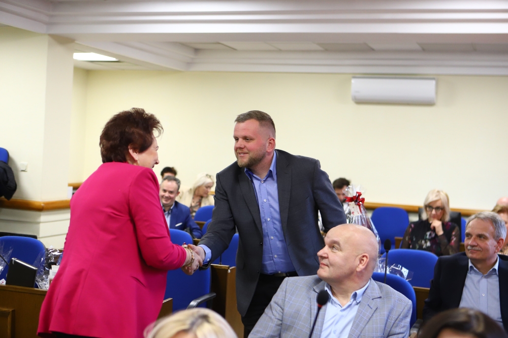 Radny uściskający dłoń radnej Ewie Kowalak