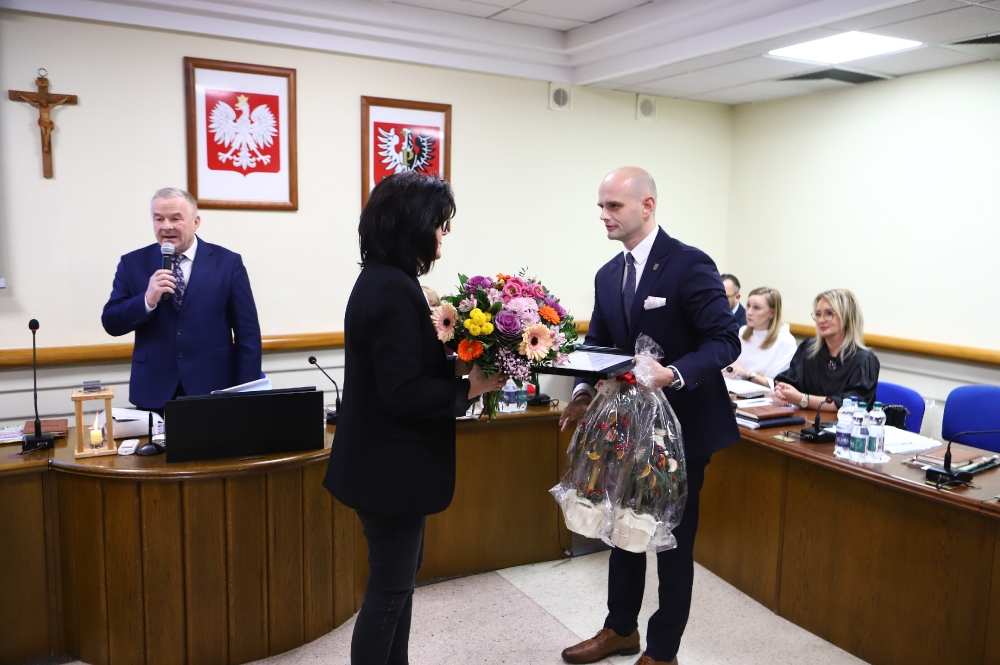 Starosta płocki wręczający upominek i kwiaty w ramach podziękowań wpółpracownicy