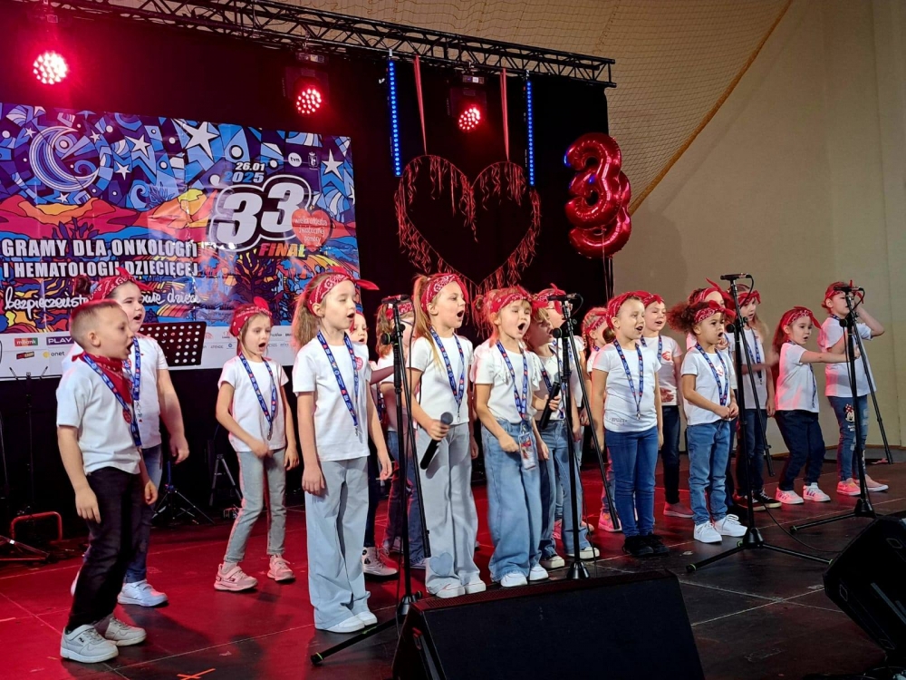 Grupa kilkunastu dzieci śpiewających na scenie podczas 33. finału WOŚP