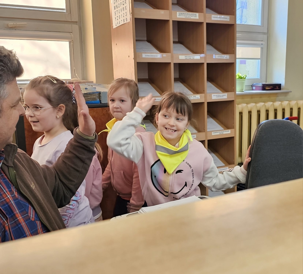 Dzieci zbijające piątkę z pracownikiem starostwa