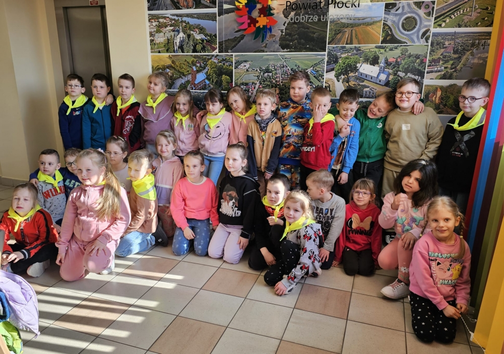 Zdjęcie grupowe dzieci na tle baneru z powiatem płockim