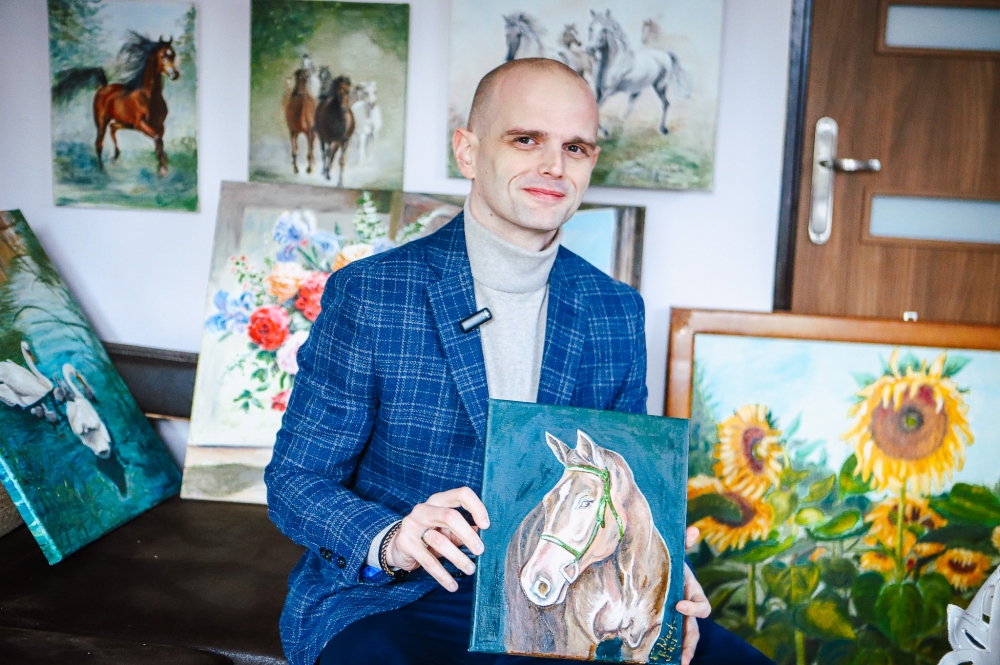 Zdjęcie starosty wraz z jedną pracą przedstawiającą konia