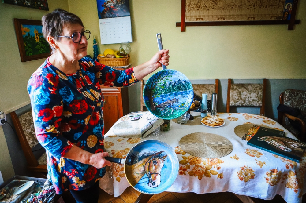 Pani Krystyna ze swoimi pracami namalowanymi na patelniach